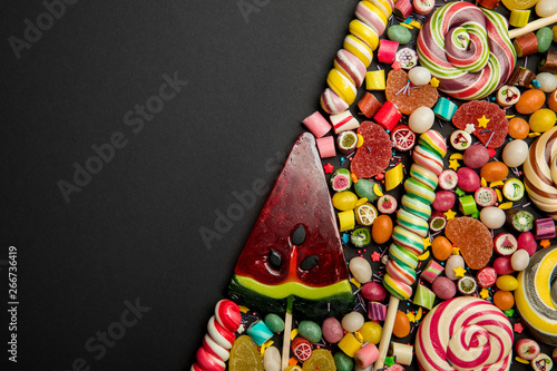 top view of delicious multicolored sweets on black background with copy space