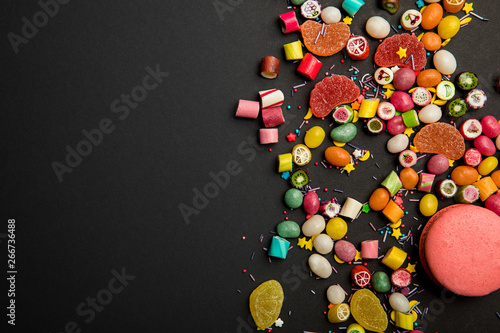 Wallpaper Mural top view of delicious multicolored candies, sprinkles and macarons on black background Torontodigital.ca