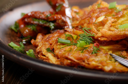 Closeup view at Homemade tasty potato pancakes in clay dish with sun-dried tomatoes