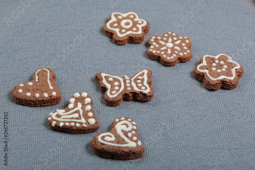 Gingerbread cookies decorated with a pattern of white glaze. On a background of gray fabric.