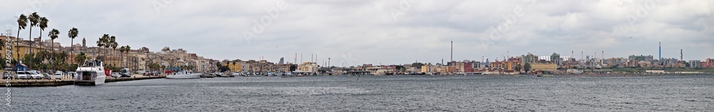 Panoramic view of Taranto, Puglia, Italy, old town with steel plant, cover of mining parks and petrochemical industry immediately behind, sunset on the sea