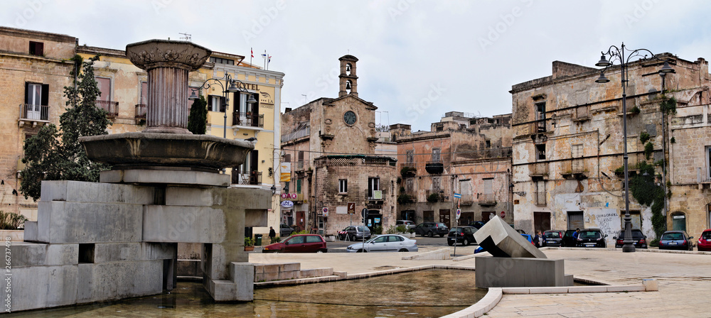 Taranto, Italy - April 20, 2019: Piazza Fontana (Fountain Square) is one of the main squares in the old town, with a modern Cubist art fountain and an ancient clock tower