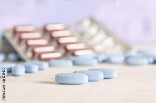 Set of three whole blue medical drug and one blister with brown pills on the table in a hospital