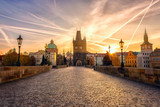 Charles bridge (Karluv most) at sunrise, scenic view of the Old town with yellow sun, colorful sky and historic medieval architecture, Prague, Czech Republic