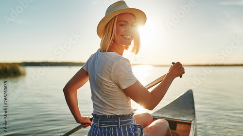 Smiling woman paddling her canoe on a lake in summer