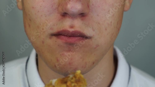 Teenager is eating the chicken wing and and wipes his lips with a wet wipe
