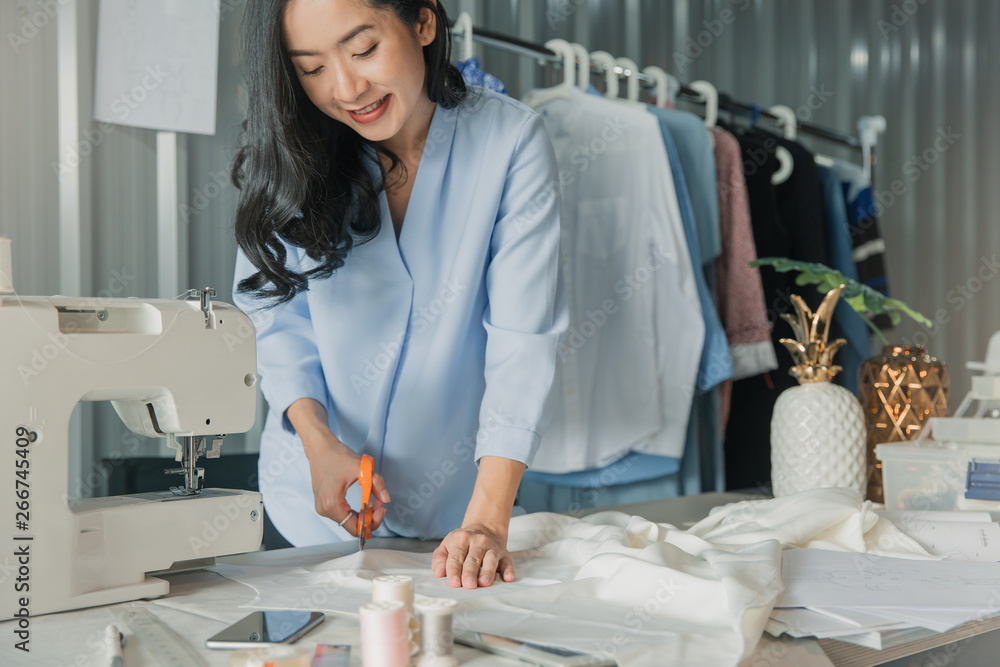 Obraz premium Young female fashion designer working on her designs in the studio. Fashion designer drawing sketches for new collection. Beautiful fashion woman designer drawing in studio .