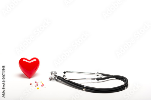 Front view of plastic red heart, stethoscopes, and drugs on white background