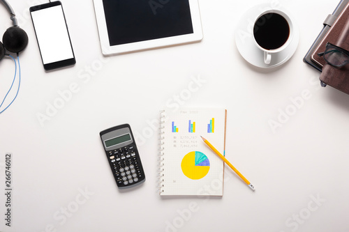 Top view of tablet  smartphone  calculator  notebook and a cup of coffee on white background