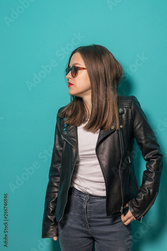 Fashioned girl in leather jacket in dark glasses in pink and blue neon lights background. 