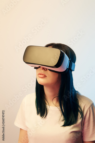 attractive brunette girl wearing virtual reality headset on beige and blue