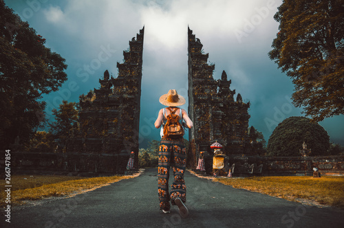 Tourist woman with backpack at vacation walking through the Hindu temple in Bali in Indonesia photo