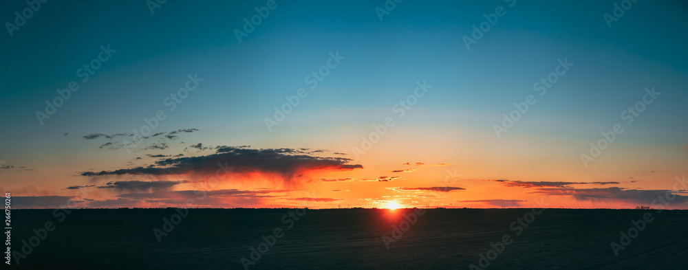 Sunset Sunrise Over Field Or Meadow. Bright Dramatic Sky And Dark Ground. Countryside Landscape Under Scenic Colorful Sky At Sunset Dawn Sunrise. Skyline, Horizon. Panorama Panoramic View