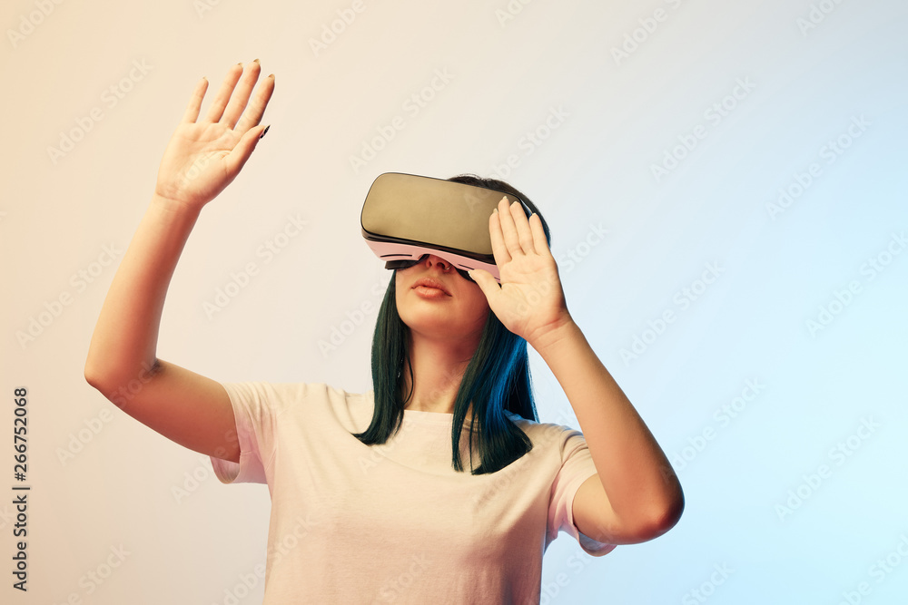 young woman wearing virtual reality headset and gesturing on beige and blue young woman wearing virtual reality headset and gesturing on beige and blue