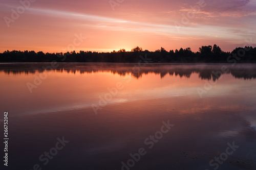 Sunrise over the forest lake. Reflection of the sky in the lake. Summer © Roman