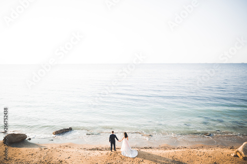 Happy and romantic scene of just married young wedding couple posing on beautiful beach