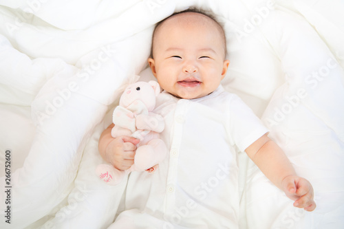 Asian baby happy in the room.Asian baby girl lying down on bed .