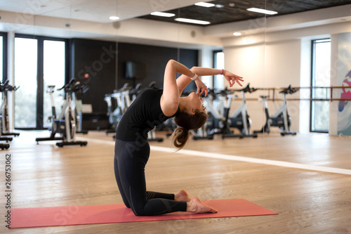The girl in the gym does yoga to keep herself in shape or control excess weight.