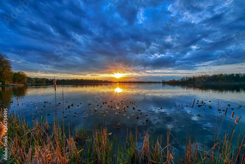 Sun on the Horizon at Sunset over Calm Water with Overcast Clouds