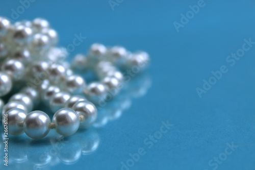 White pearl necklace lying on a blue background