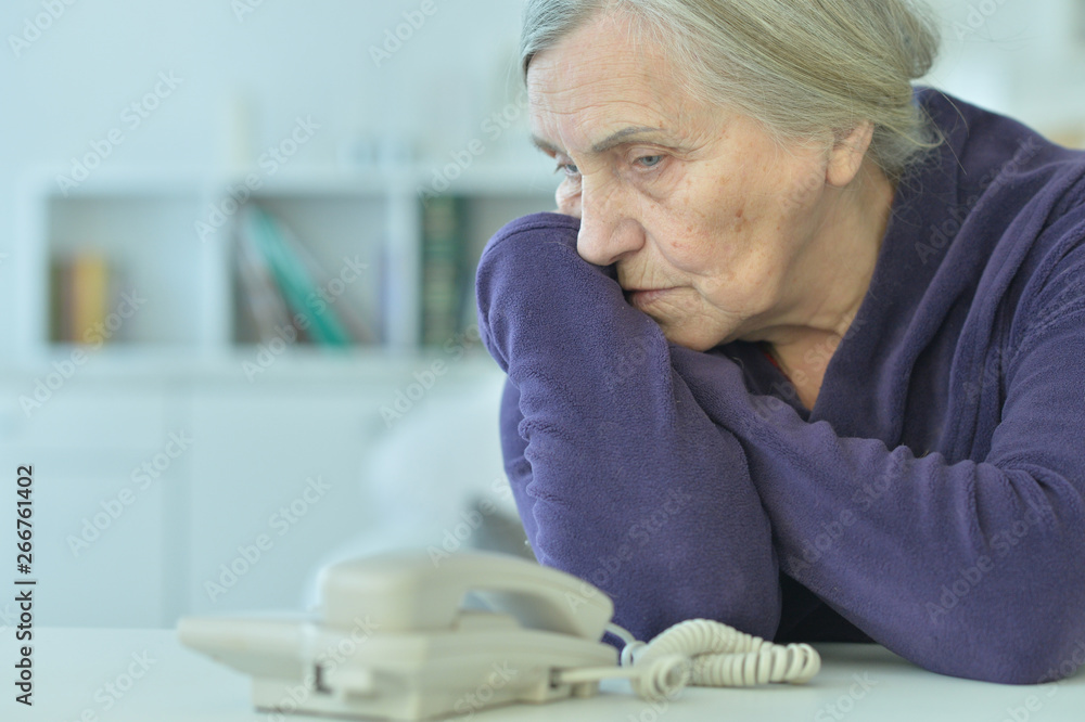 Obraz premium Portrait of a sad elderly woman looking at phone