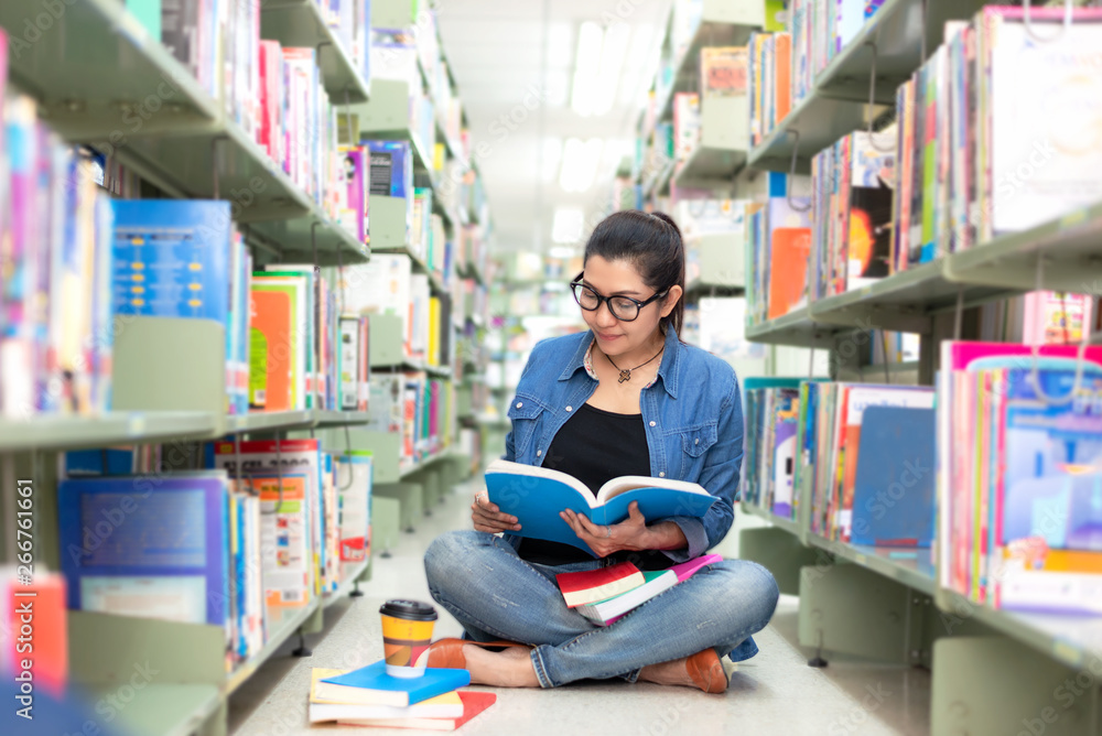 Asian women in library reading something in a book and choosing a book in a library. Education Concept Asian women in library reading something in a book and choosing a book in a library. Education Concept