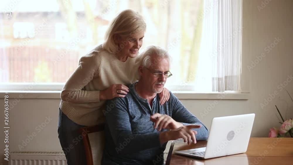 Elderly positive couple using computer new application or online banking Elderly positive couple using computer new application or online banking