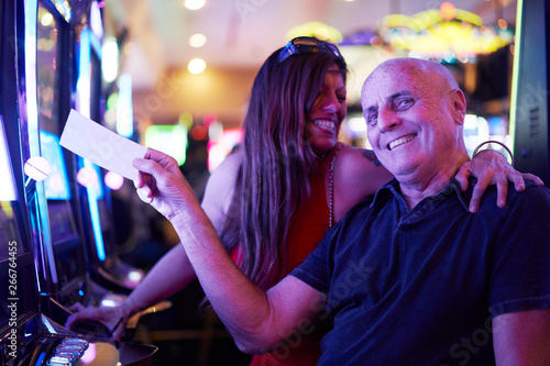Sticker happy mature couple with payout ticket at casino
