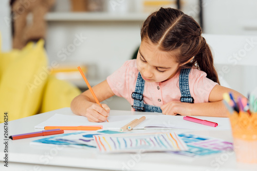 selective focus of cute kid drawing on paper at home