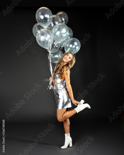 Pretty young woman in flirty pose with silver party balloons.  