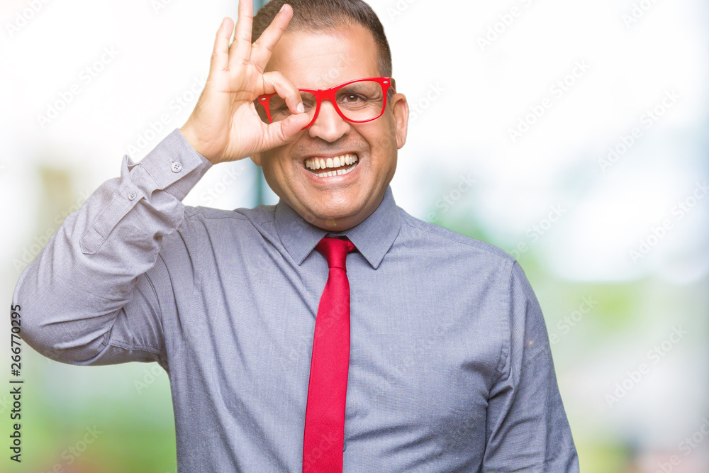 Middle age arab man wearing fashion red glasses over isolated background doing ok gesture with hand smiling, eye looking through fingers with happy face.