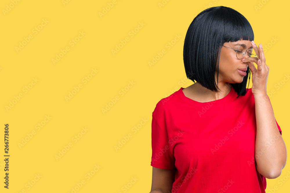 Beautiful young african american woman wearing glasses over isolated background smelling something stinky and disgusting, intolerable smell, holding breath with fingers on nose. Bad smells concept. Beautiful young african american woman wearing glasses over isolated background smelling something stinky and disgusting, intolerable smell, holding breath with fingers on nose. Bad smells concept.