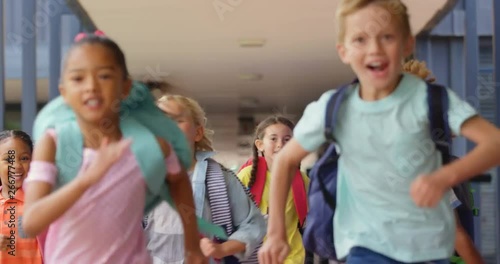 Front view of mixed-race schoolkids with schoolbags running in the corridor at school 4k photo