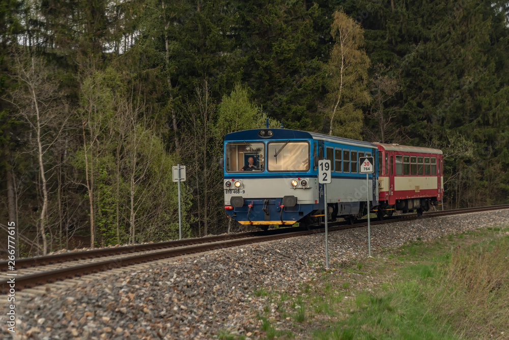 Blue and red diesel train with passengers coach in Jeseniky mountains