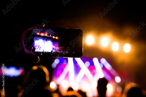 Picture of a lot of people enjoying night perfomance  large unrecognizable crowd dancing with raised up hands and mobile phones on concert. nightlife