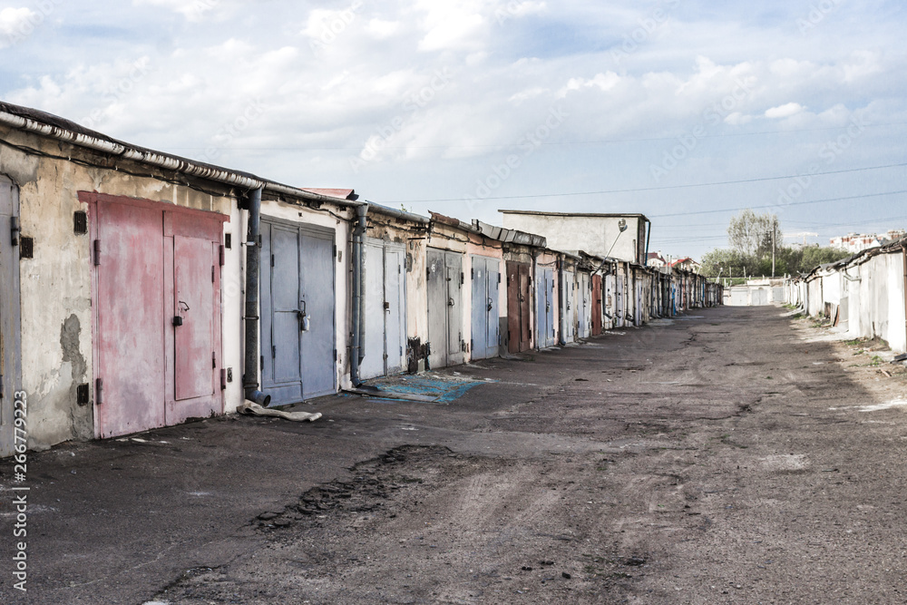 Garage cooperative. Rows of car garages. City architecture. Transport industry. Stone sheds. Rusty iron gate. Brick wall. Perspective in architecture. Abandoned area. Deserted street. Garage cooperative. Rows of car garages. City architecture. Transport industry. Stone sheds. Rusty iron gate. Brick wall. Perspective in architecture. Abandoned area. Deserted street.