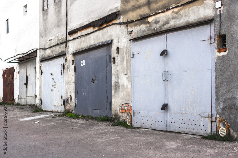 Garage cooperative. Rows of car garages. City architecture. Transport industry. Stone sheds. Rusty iron gate. Brick wall. Perspective in architecture. Abandoned area. Deserted street. Garage cooperative. Rows of car garages. City architecture. Transport industry. Stone sheds. Rusty iron gate. Brick wall. Perspective in architecture. Abandoned area. Deserted street.