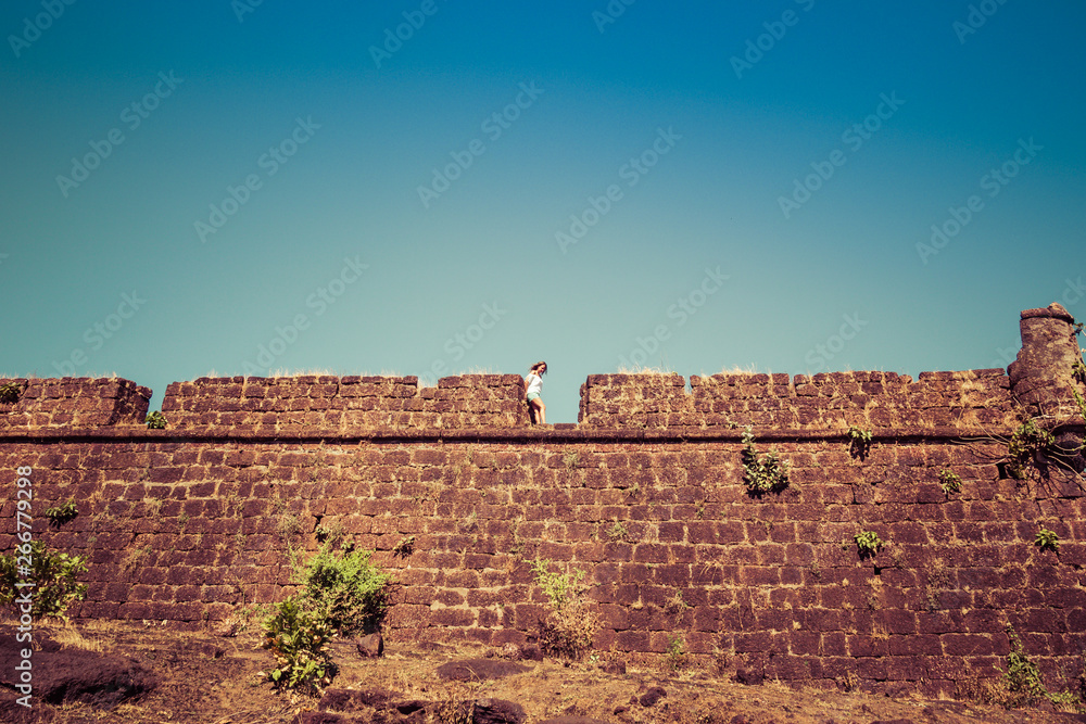 Young woman stands on the brick wall of the old fort