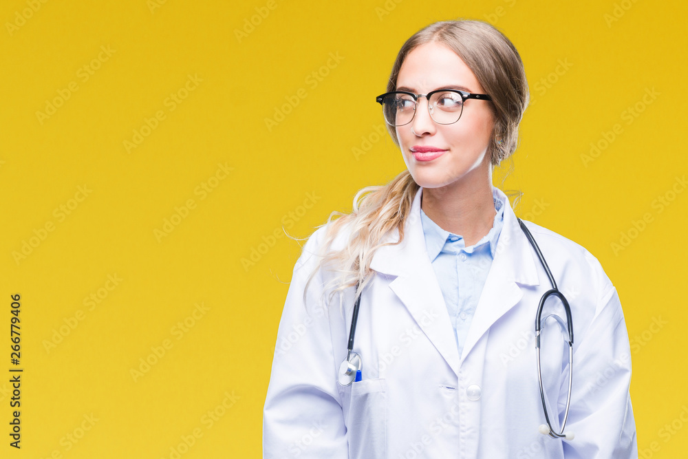 Beautiful young blonde doctor woman wearing medical uniform over isolated background smiling looking side and staring away thinking. Beautiful young blonde doctor woman wearing medical uniform over isolated background smiling looking side and staring away thinking.