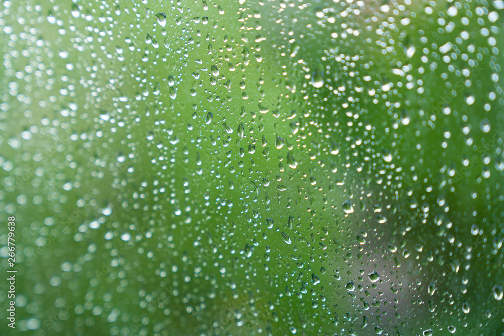Drops of rain on glass with green background texture
