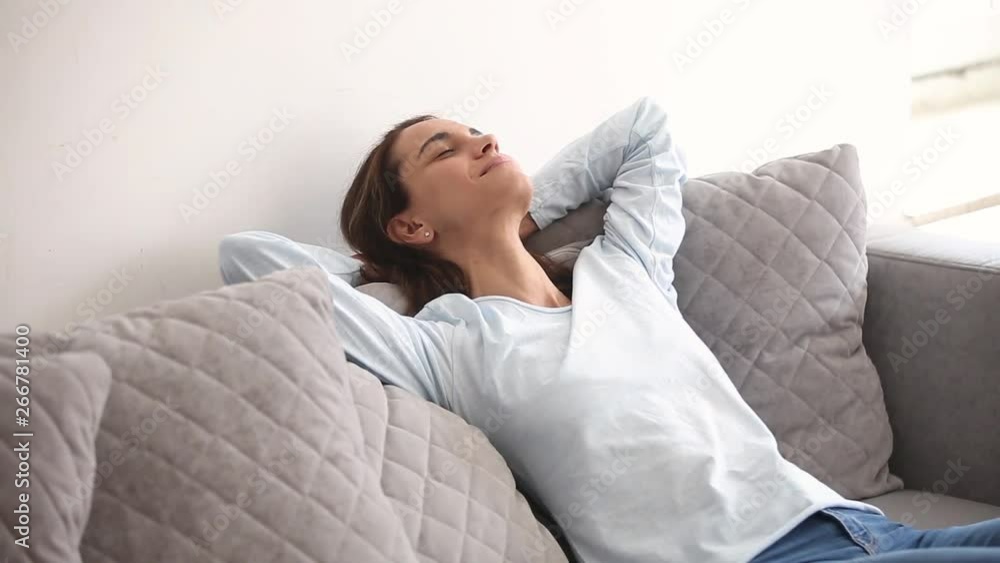 Millennial woman closed eyes resting on comfortable couch at home