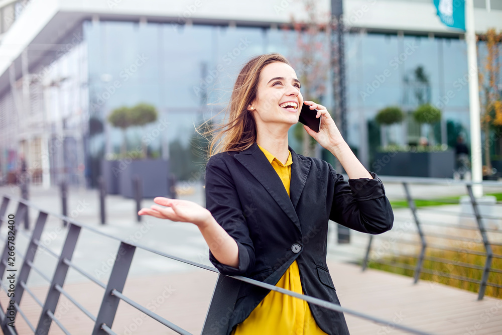 Fototapeta premium Businesswoman with a mobile phone in the street with office buildings in the background