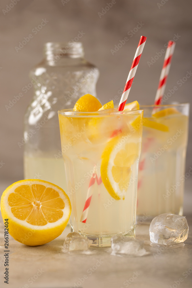two glasses of lemonade with lemons and lime and straw, a bottle with a cool drink and summer mood, with ice, freshness in hot summer two glasses of lemonade with lemons and lime and straw, a bottle with a cool drink and summer mood, with ice, freshness in hot summer