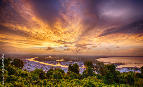 Colorful dramatic sky with dark cloud at sunset sky with the forest, mountains, villages and factories in the foreground, Ban Pak Nam, Chumphon, Thailand.