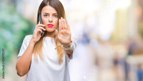 Young beautiful woman speaking calling using smartphone over isolated background with open hand doing stop sign with serious and confident expression  defense gesture