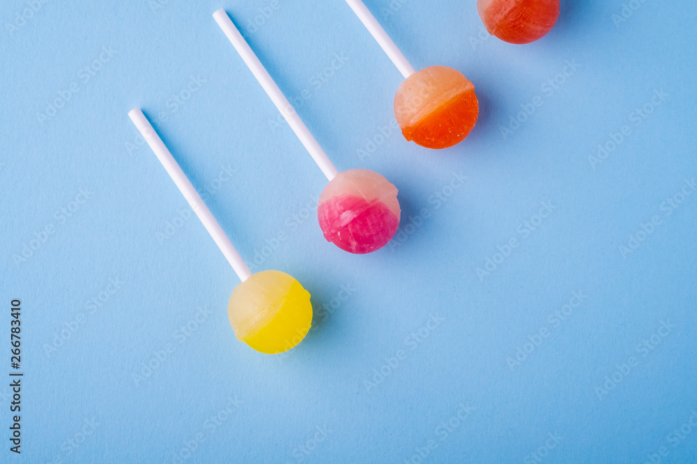 Lollipop candies in diagonal row on blue background top view Lollipop candies in diagonal row on blue background top view