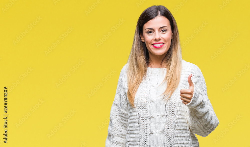 Young beautiful woman casual white sweater over isolated background doing happy thumbs up gesture with hand. Approving expression looking at the camera with showing success. Young beautiful woman casual white sweater over isolated background doing happy thumbs up gesture with hand. Approving expression looking at the camera with showing success.