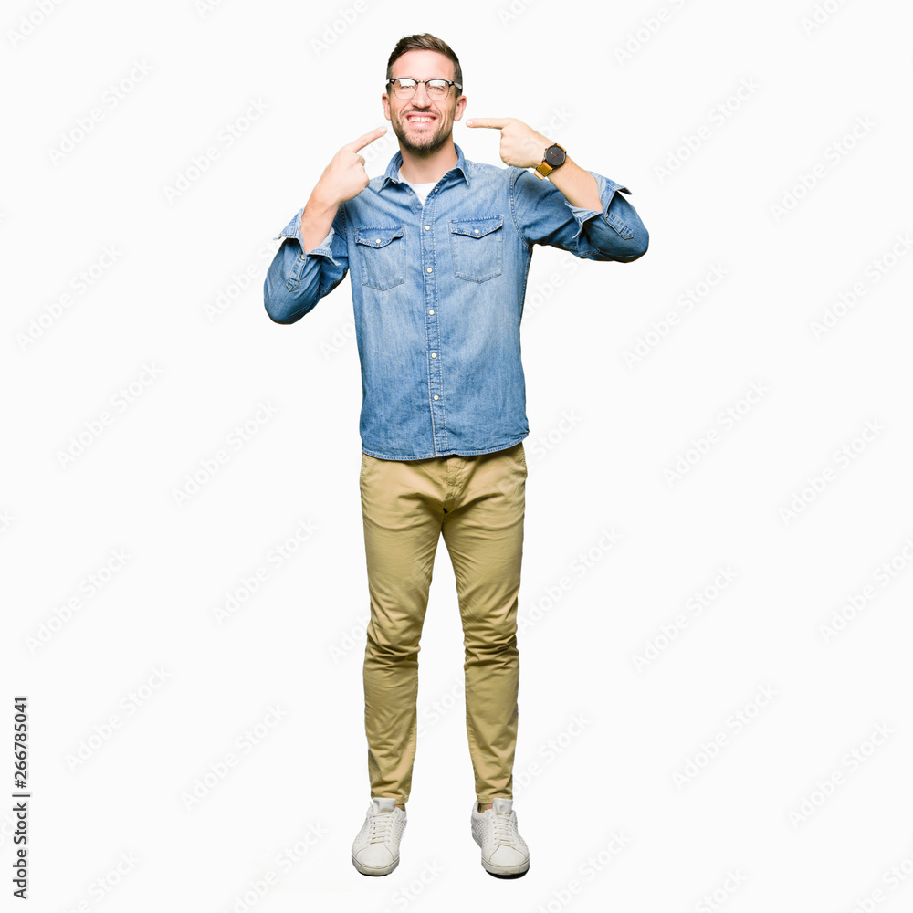 Handsome man wearing glasses smiling confident showing and pointing with fingers teeth and mouth. Health concept. Handsome man wearing glasses smiling confident showing and pointing with fingers teeth and mouth. Health concept.