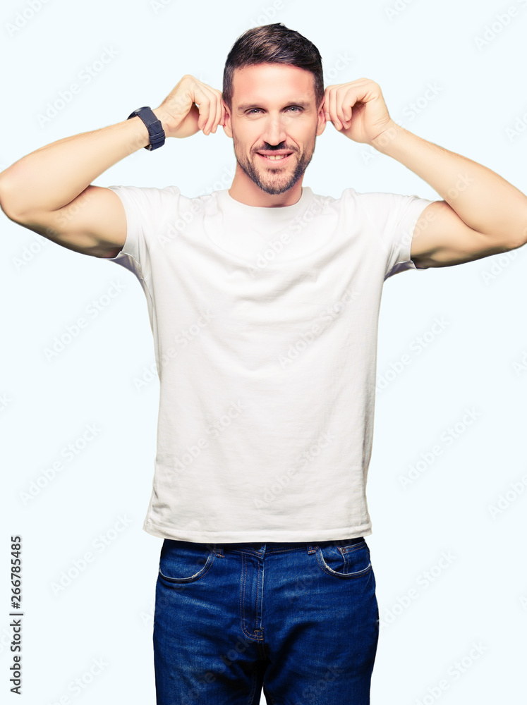 Handsome man wearing casual white t-shirt Smiling pulling ears with fingers, funny gesture. Audition problem Handsome man wearing casual white t-shirt Smiling pulling ears with fingers, funny gesture. Audition problem