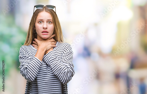 Young beautiful blonde woman wearing sunglasses over isolated background shouting and suffocate because painful strangle. Health problem. Asphyxiate and suicide concept.